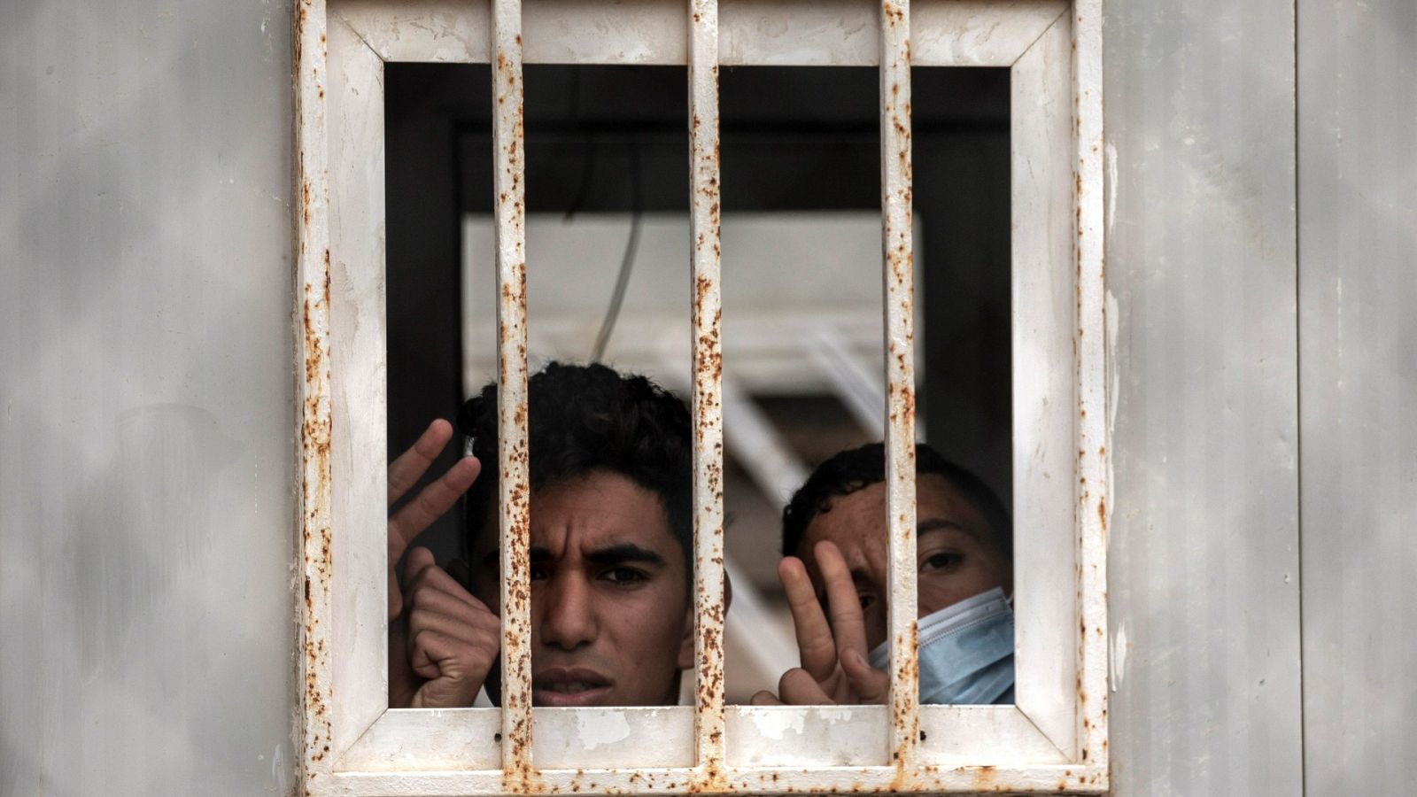 Dos menores saludan por una ventana del albergue de Piniers, en Ceuta