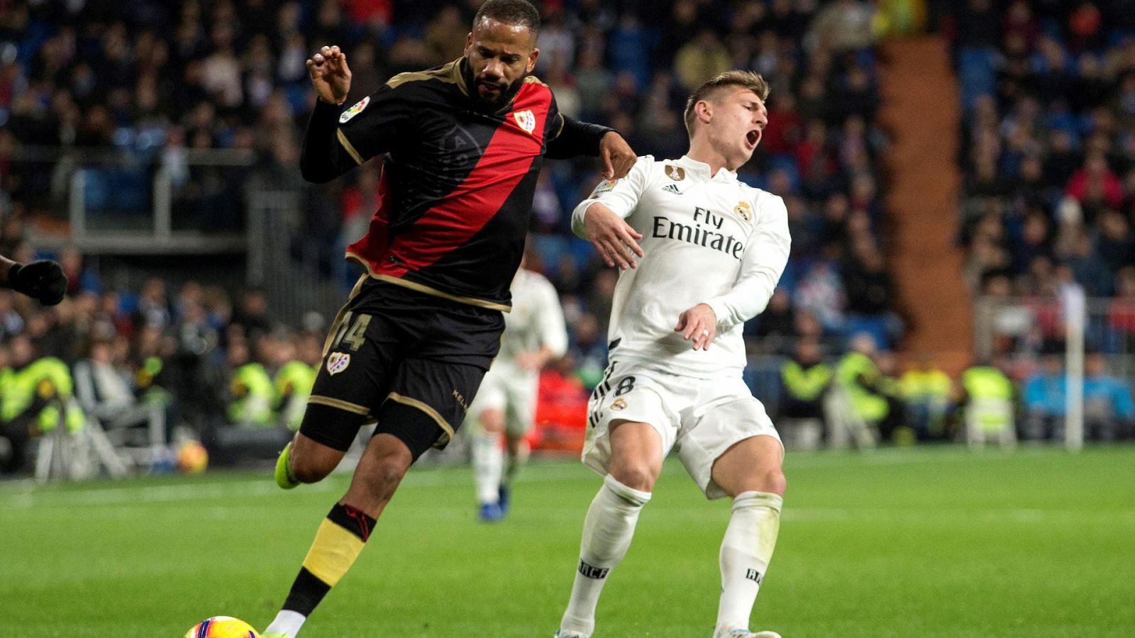 El centrocampista del Real Madrid Toni Kroos (d) lucha por el balón ante el delantero del Rayo Vallecano Bebé durante un partido de la Liga 2018/19