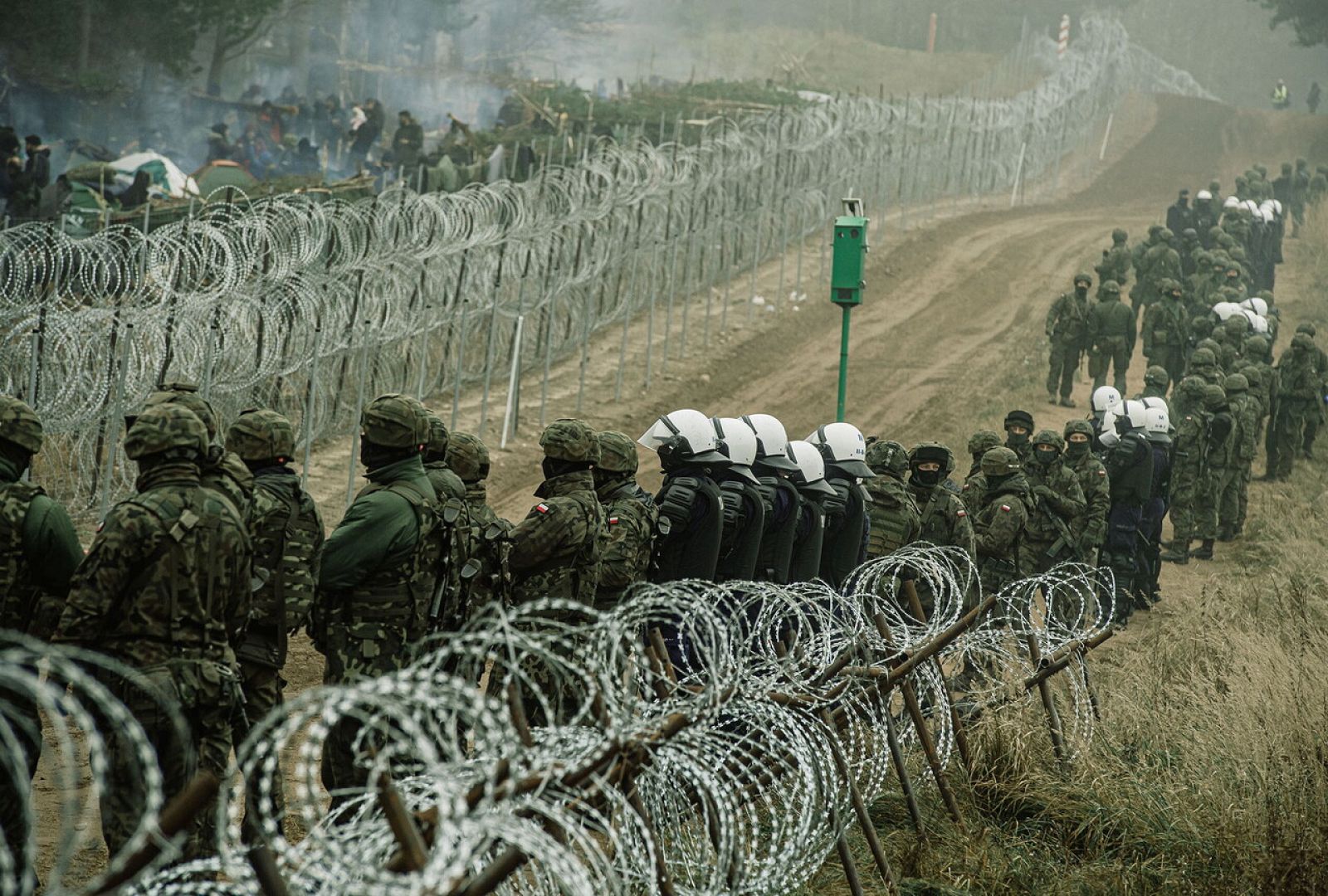 Soldados y policías polacos apostados en la valla fronteriza con Bielorrusia cerca de Kuznica. Enfrente, mientras que quieren entrar en la UE. Irek Dorozanski/DWOT/vía REUTERS 