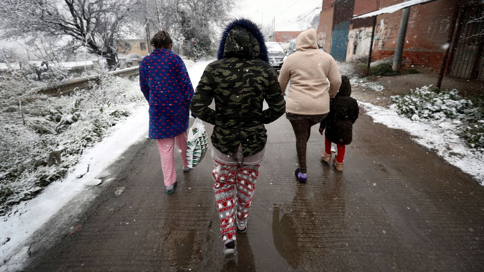 Varios residentes del asentamiento de la Cañada Real caminan bajo la nieve durante el temporal Filomena