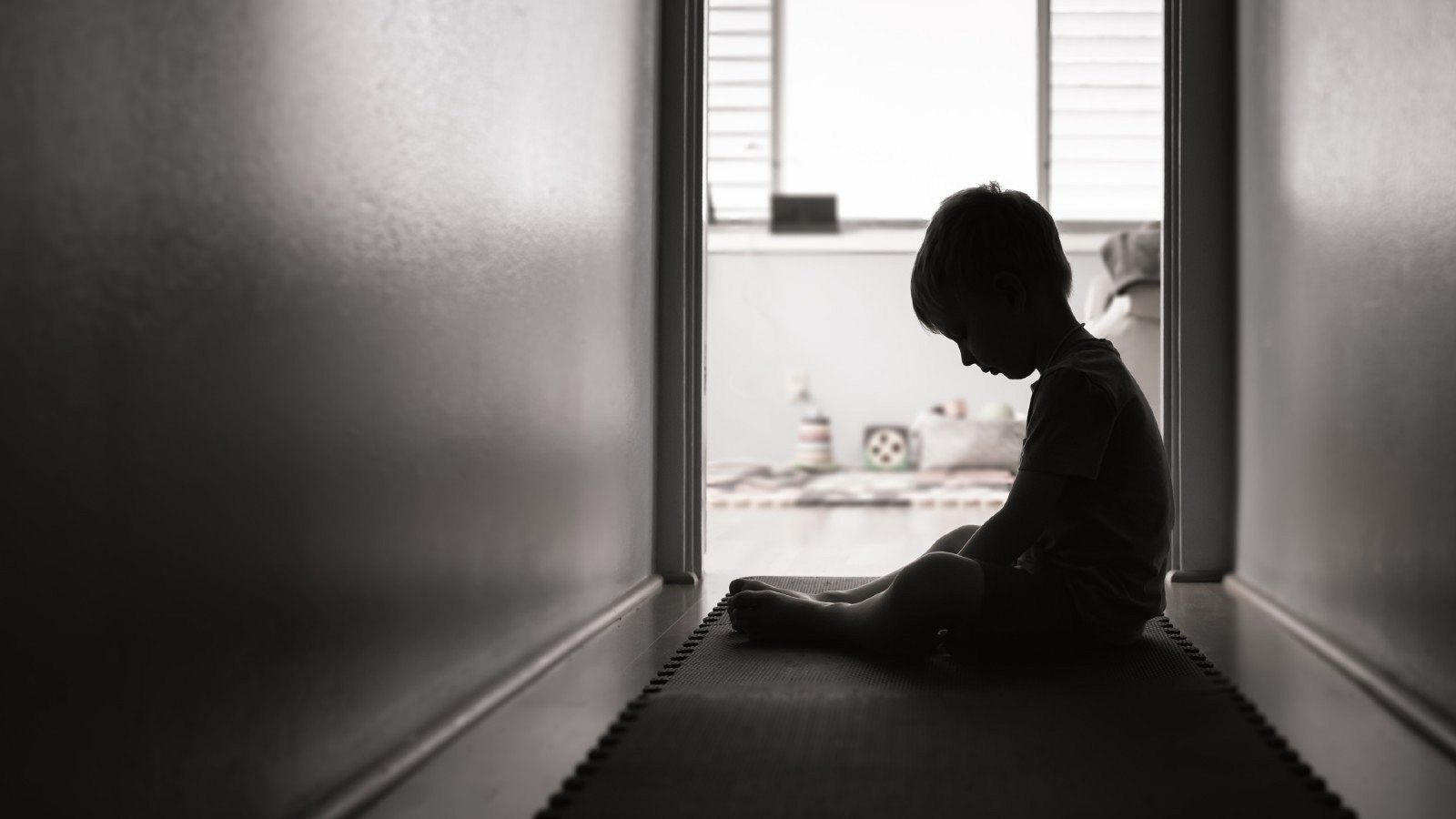 La silueta de un niño, triste, frente a la puerta de su habitación, en una imagen de archivo.