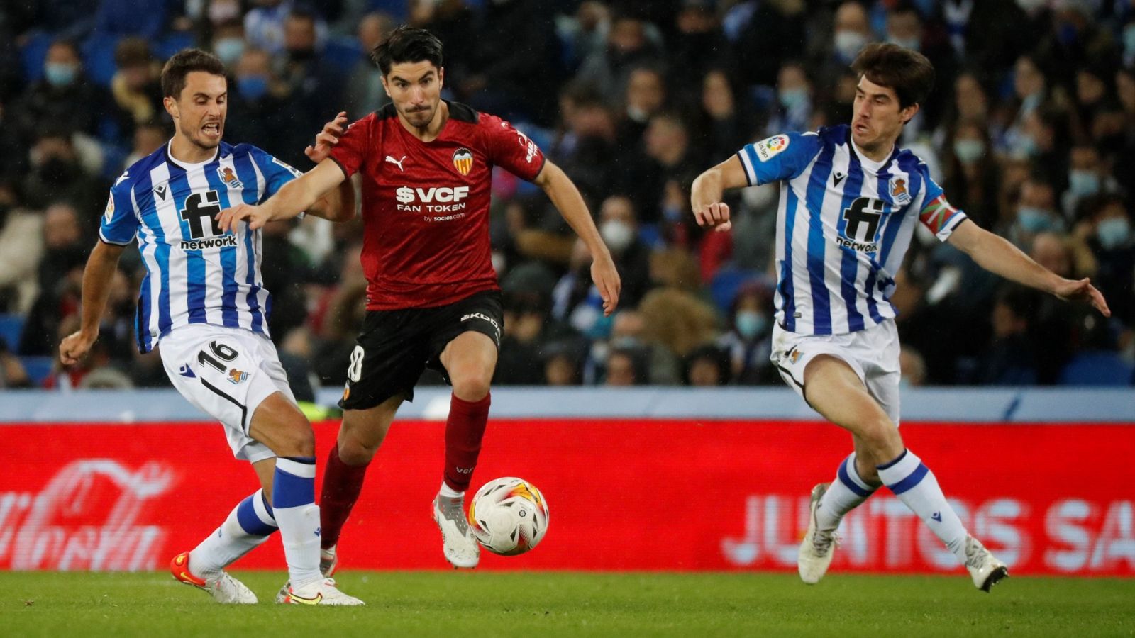 El centrocampista del Valencia CF Carlos Soler (c) se escapa de Ander Guevara (i), de la Real Sociedad