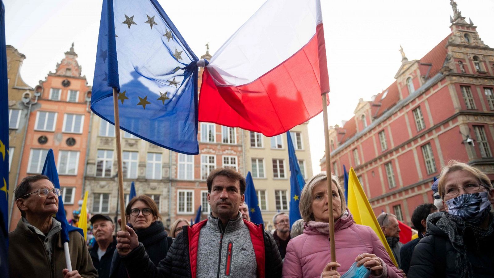 Un grupo de personas sostienen banderas de Polonia y Europa
