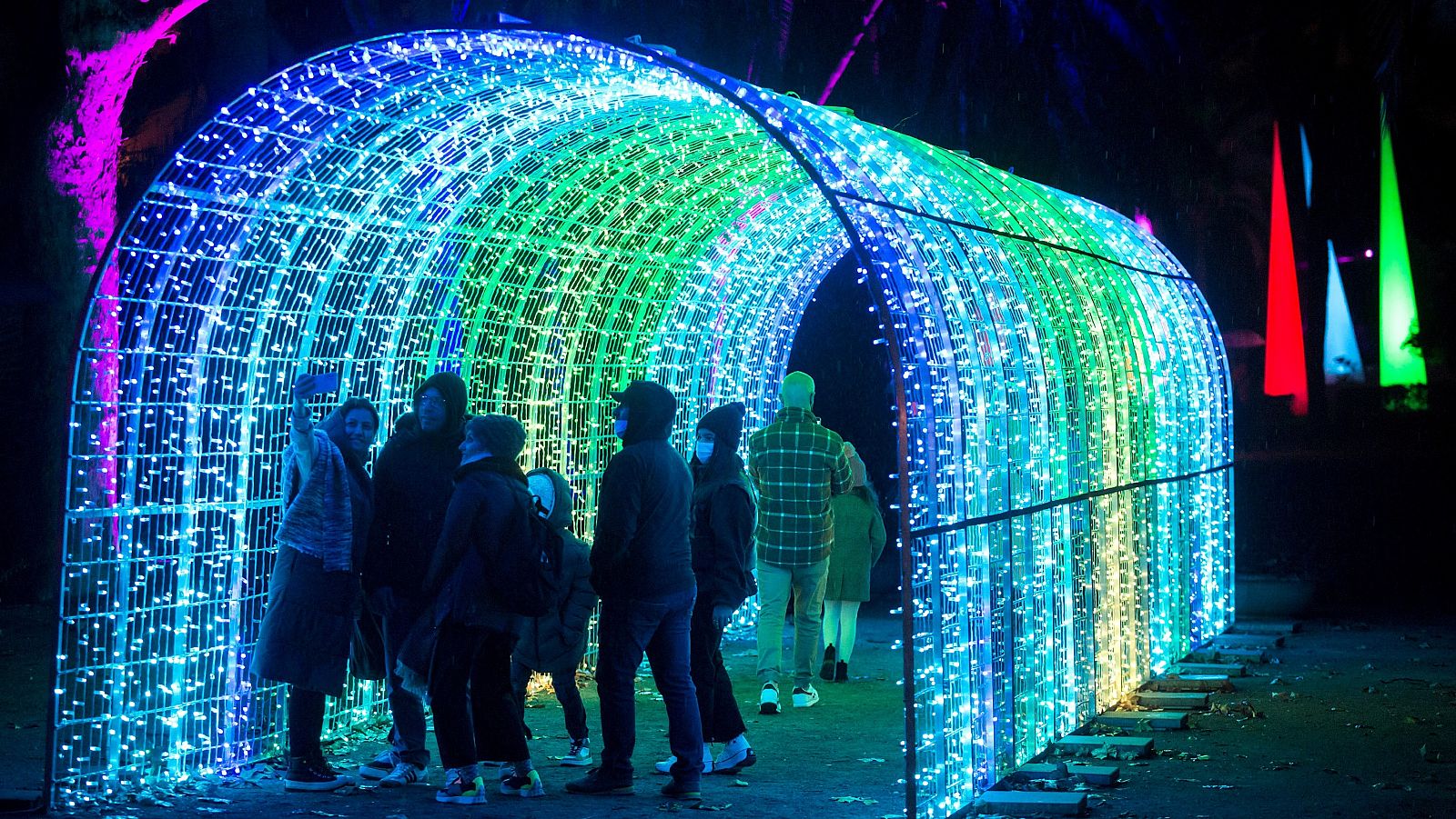 Un grupo de personas se fotografía en el Jardín Botánico Histórico La Concepción, en Málaga, junto a luces navideñas.