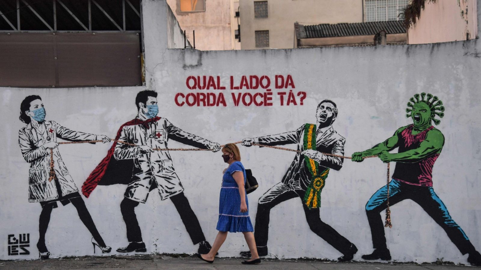 Una mujer pasando frente a un mural sobre la COVID-19 en una calle de Sao Paulo, Brasil.
