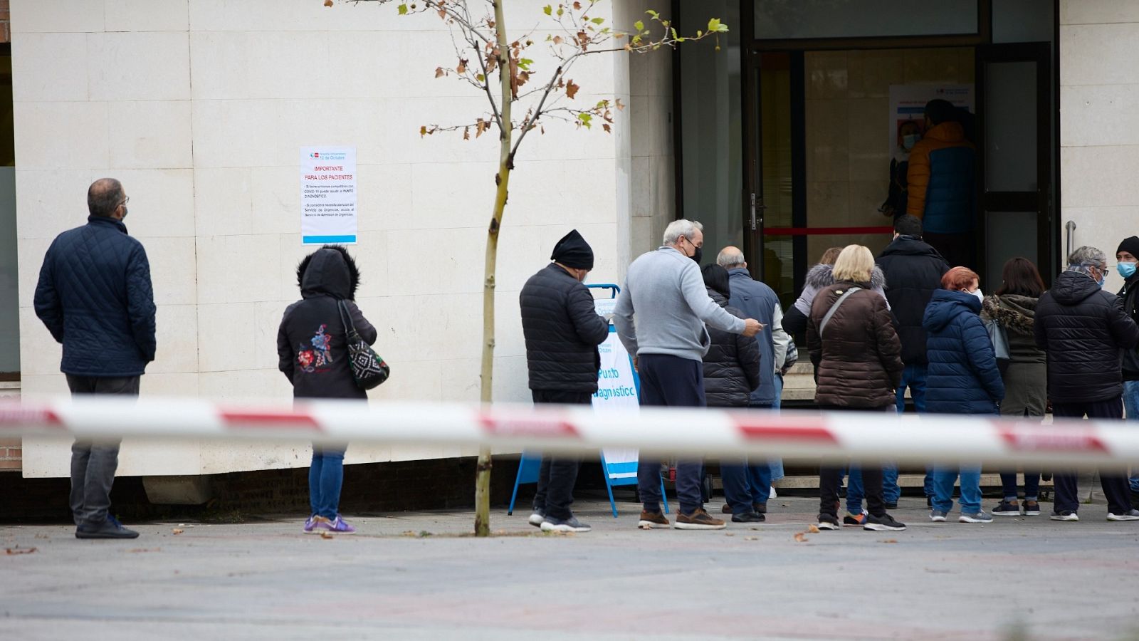 Varias personas esperan la cola en las inmediaciones del Hospital 12 de Octubre de Madrid para hacerse PCR.