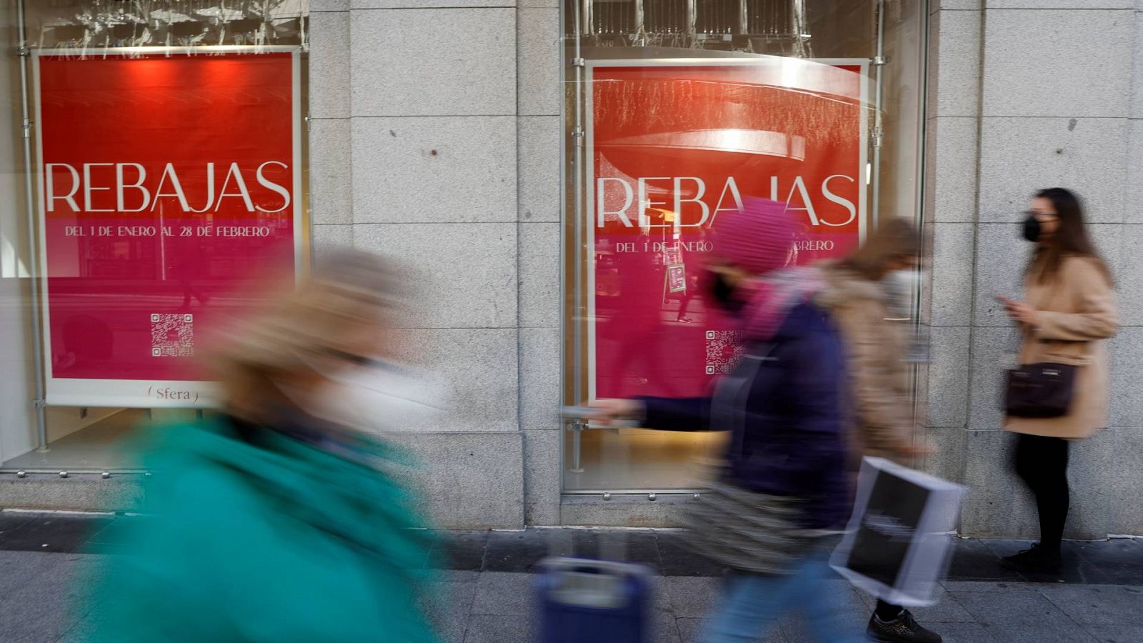 Varias personas pasan ante un comercio en Madrid que ya cuelga los carteles de rebajas