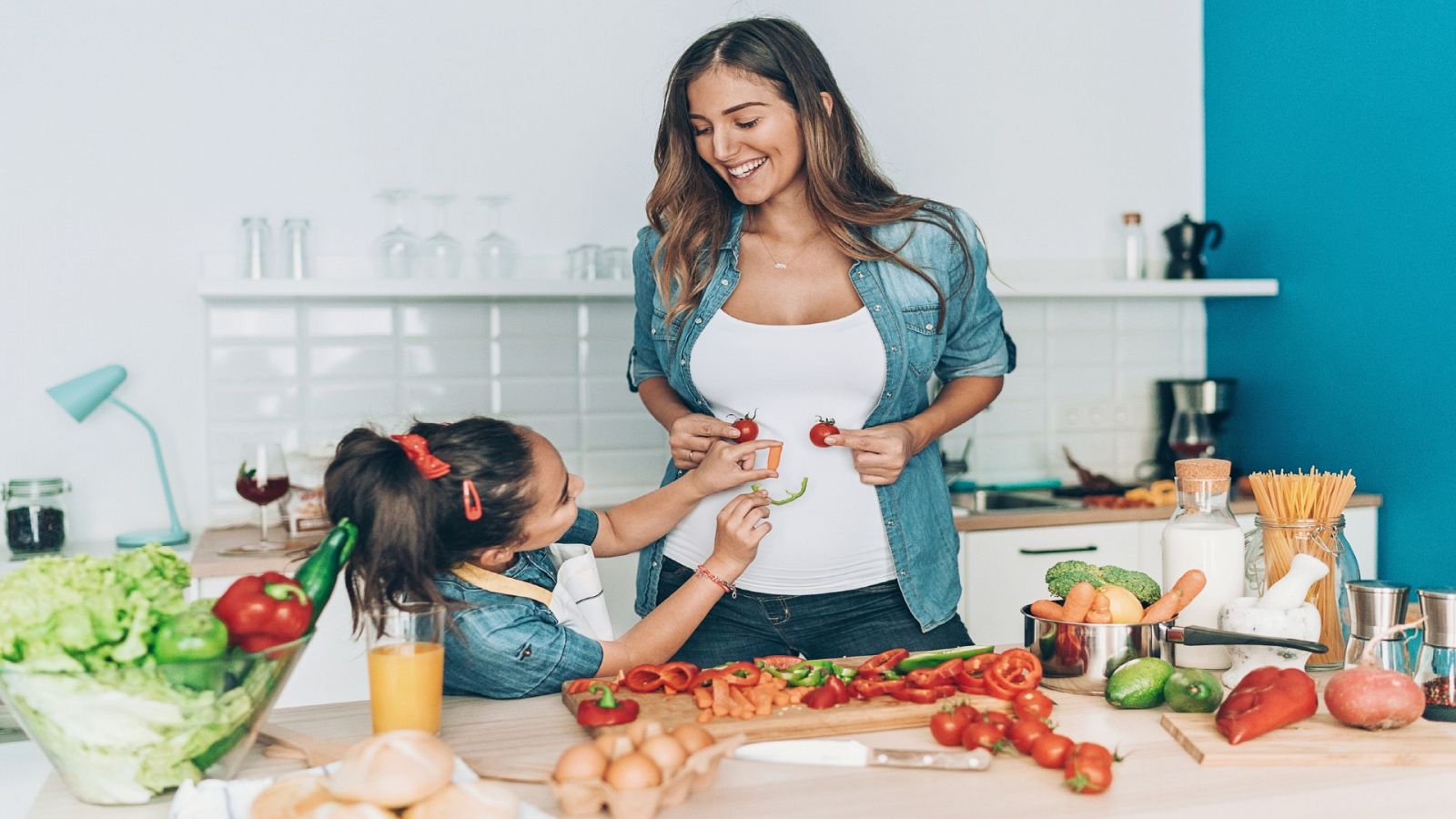 Una mujer y una niña pequeña cortando verduras en la cocina