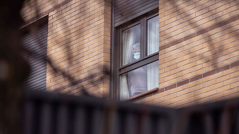 Una mujer observa desde el interior de la residencia para mayores