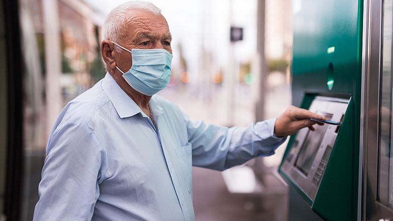 Una persona mayor saca dinero de un cajero