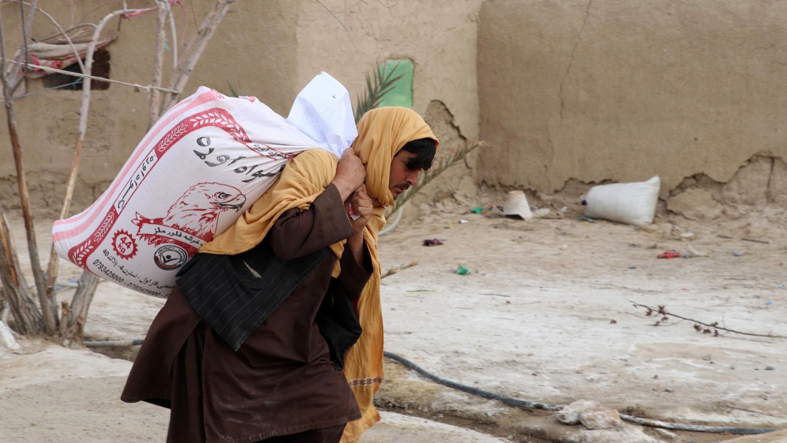 Una persona carga con su ración de alimento, distribuida por la Afghan Charity Foundation en Kandahar, Afganistán