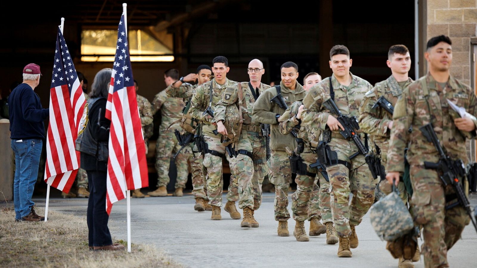 Soldados de la 82ª División Aerotransportada del Ejército de EE.UU. pasan junto a unos veteranos con banderas nacionales en Fort Bragg (Carolina del Norte, EE.UU.), antes de volar hacia Europa. REUTERS/Jonathan Drake