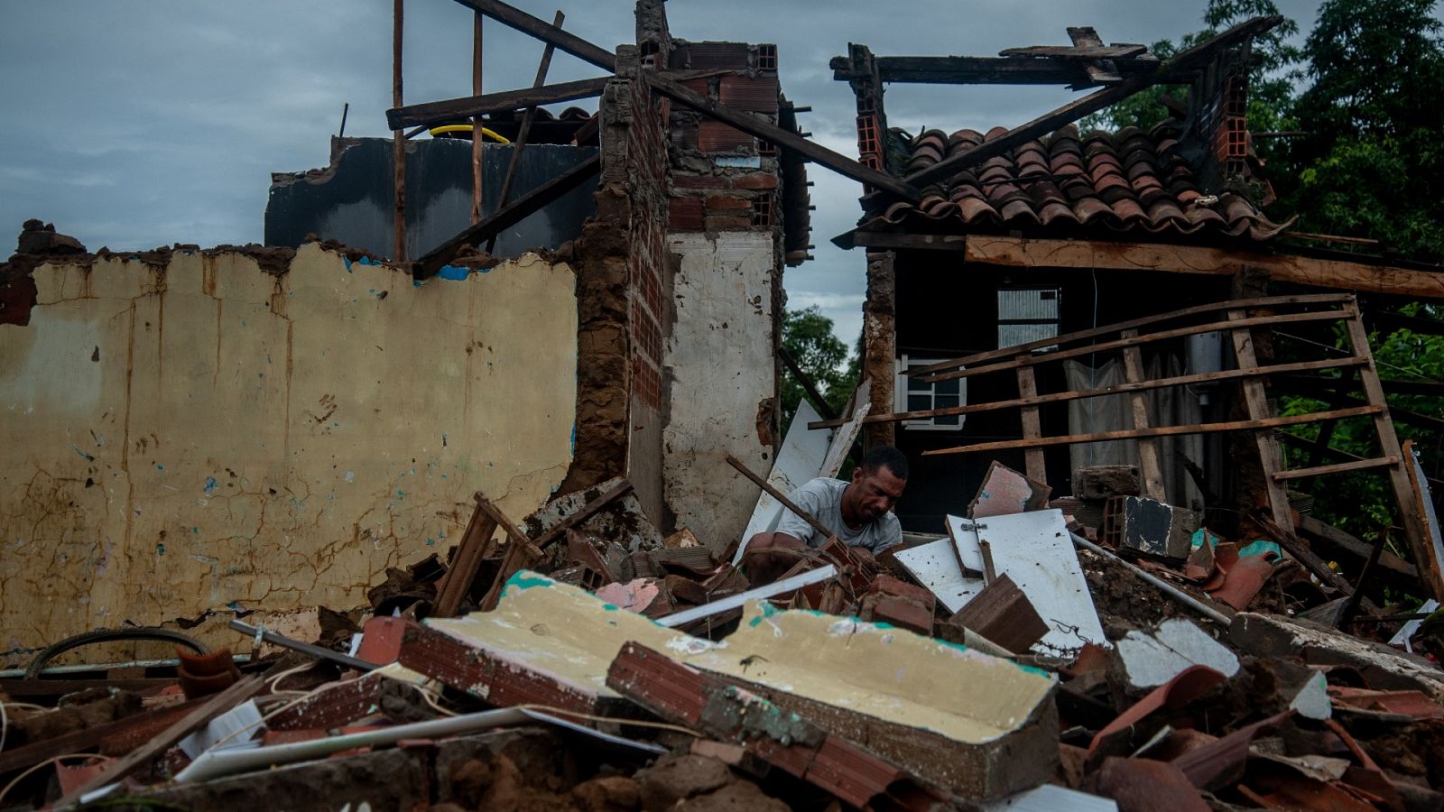 Un hombre trata de rescatar sus pertenencias de su casa destruida por inundaciones