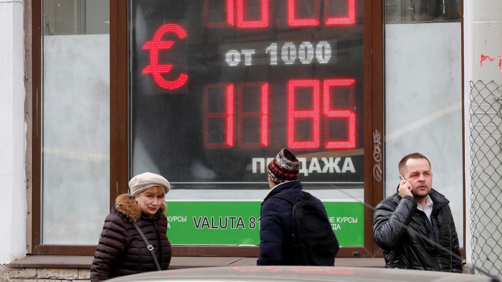 Varias personas caminan frente a un panel que muestra el tipo de cambio del euro y el dólar en una oficina de San Petersburgo, Rusia.