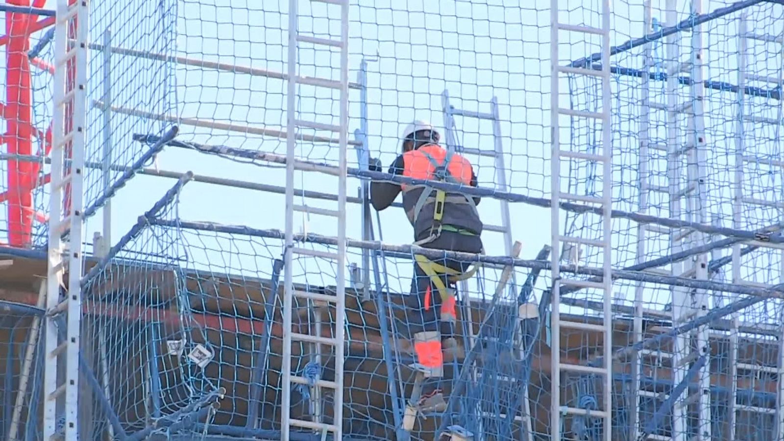 Un obrer operant una grua mentre es construeix un edifici