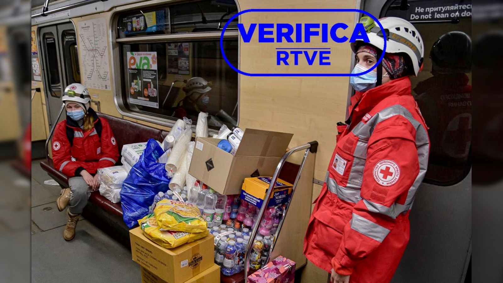 Dos voluntarias de la Cruz Roja con cajas de alimentos en el metro de Kyev (Ucrania) con el sello: VerificaRTVE