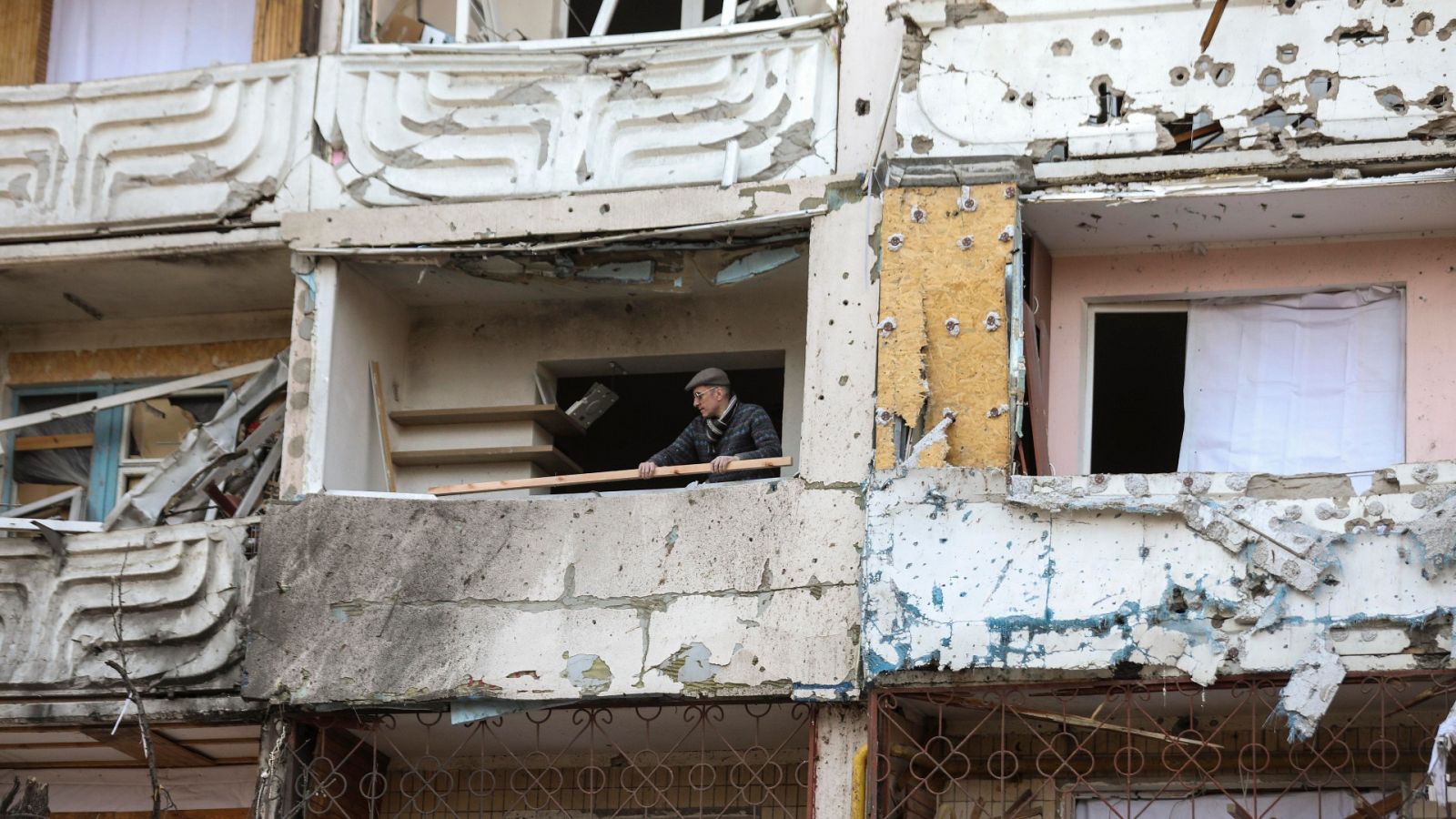 Un hombre limpia los escombros de un edificio dañado por los bombardeos en Kiev, Ucrania