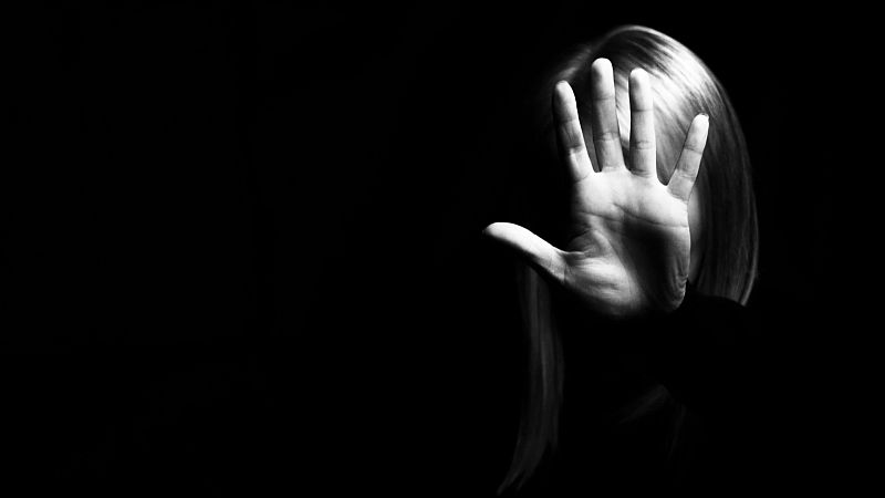 una mujer se defiende con la mano delante de su rostro