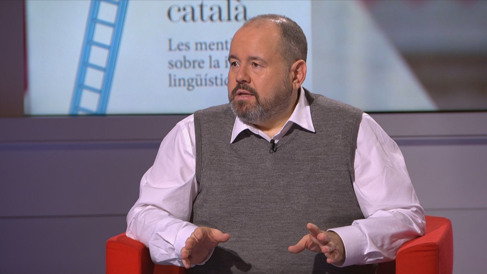  Joan Mena al plató del programa assegut a un sofà vermell