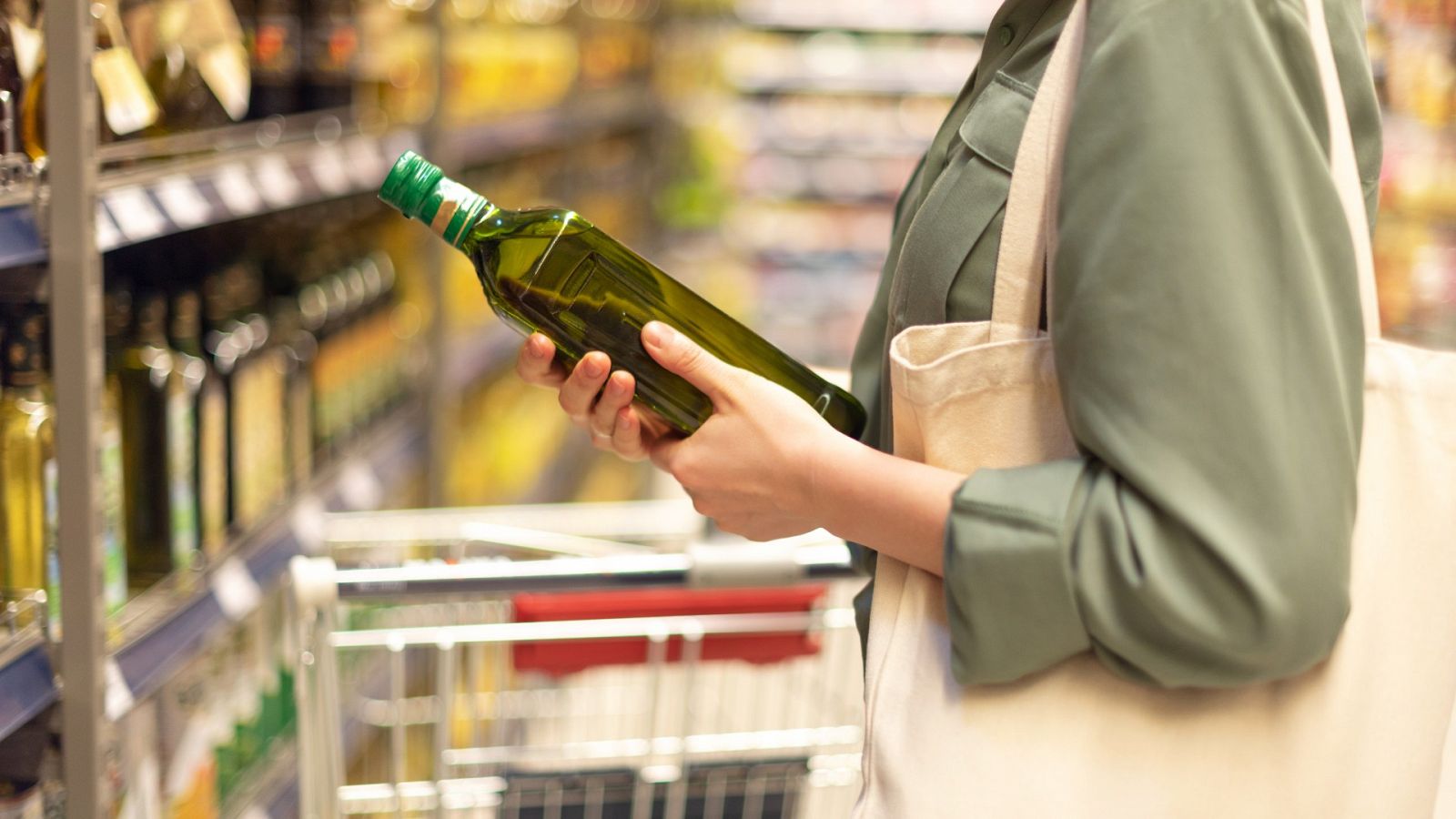 Una mujer mira el etiquetado de una botella de aceite en el supermercado