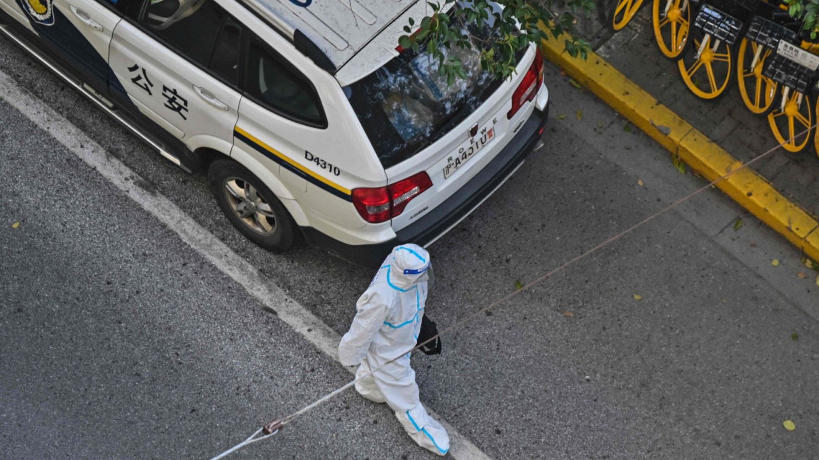 Un policía llevando un traje de protección personal contra la COVID-19 caminando por una calle de Shanghái.