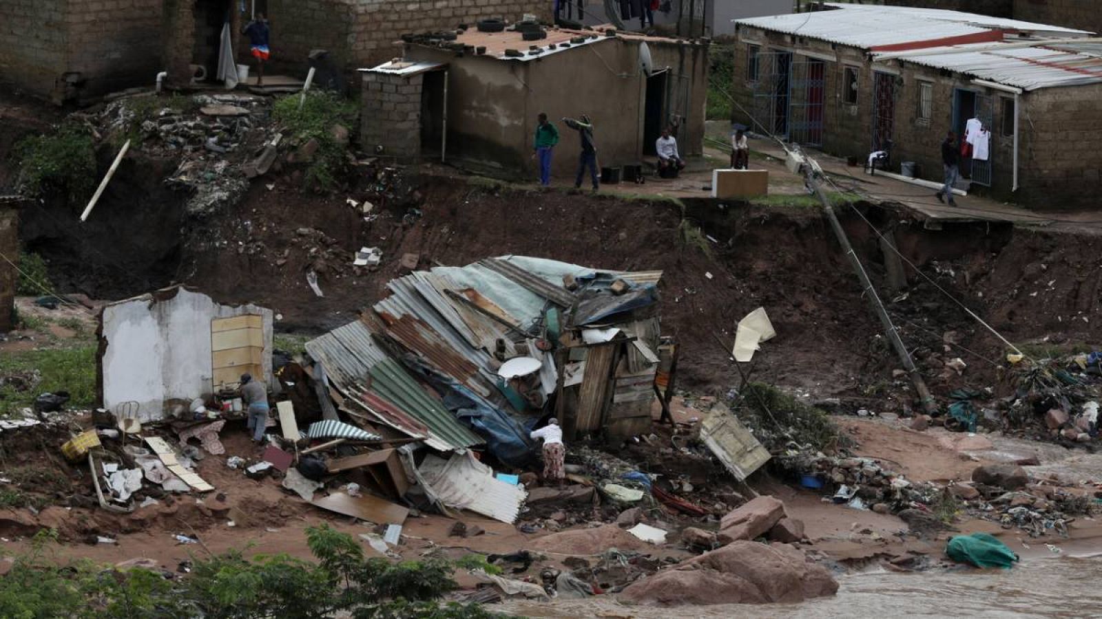 Una familia revisa lo que queda de su choza después de que las aguas de la inundación la destruyeran, Durban, Sudáfrica.