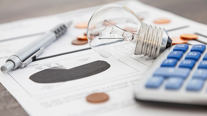 Una bombilla junto a una calculadora encima de una factura