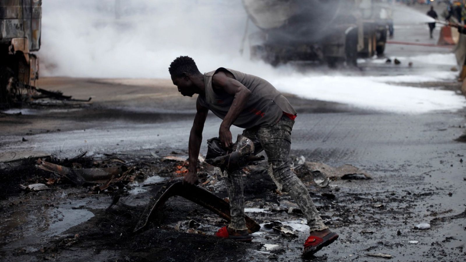 Imagen de archivo de un un hombre recogiendo escombros quemados tras la explosión de un camión cisterna de petróleo en Nigeria.