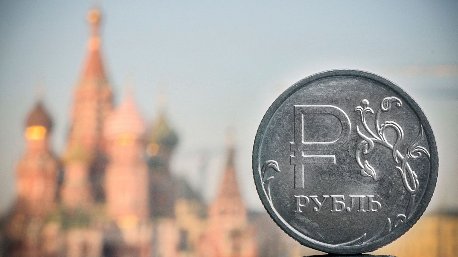 Una moneda de rublo ruso frente a la catedral de San Basilio en el centro de Moscú, Rusia.