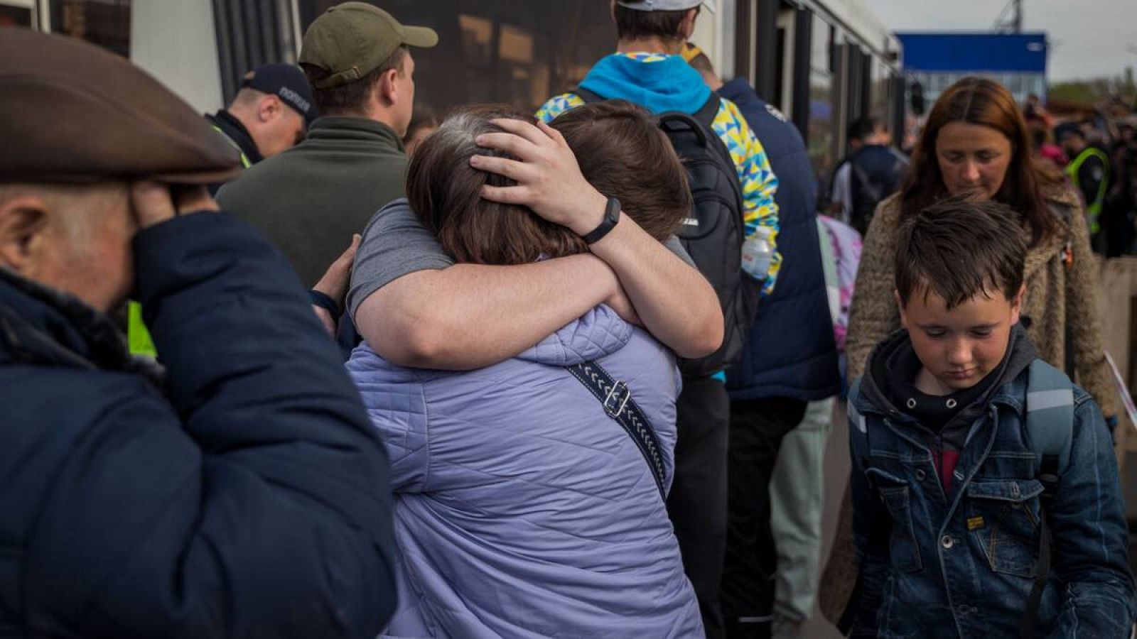 Refugiados se abrazan tras llegar al estacionamiento de un centro comercial en Zaporiyia (Ucrania).