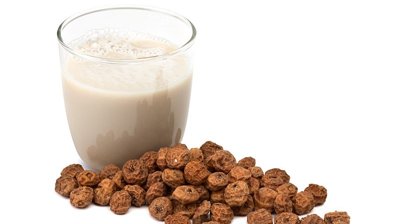 Un vaso de horchata junto al tubérculo del que se obtiene, la chufa