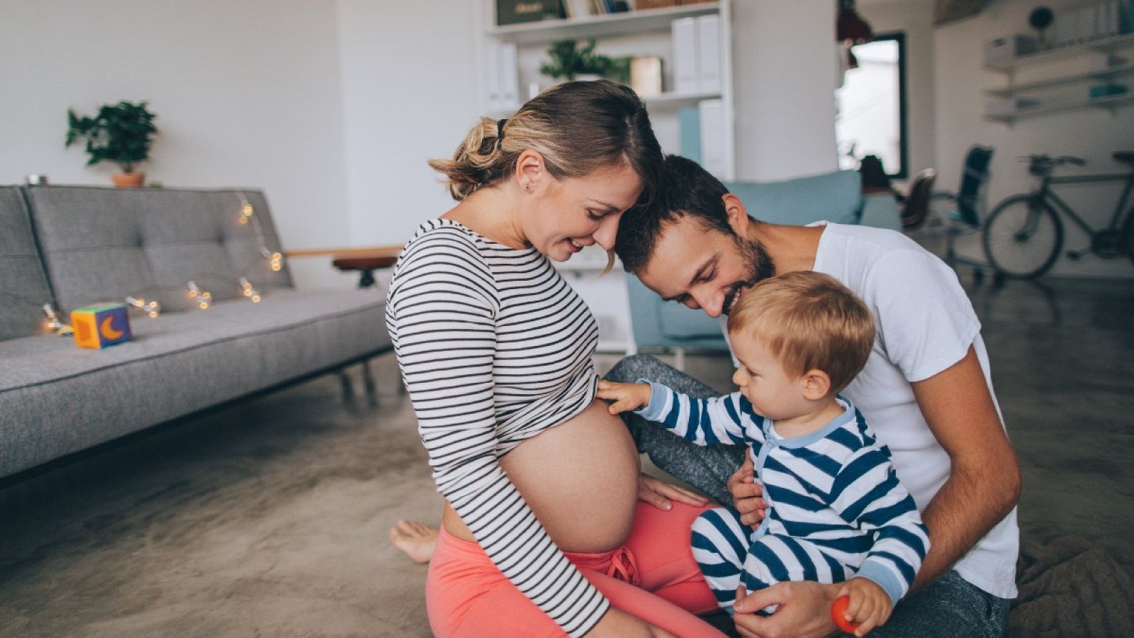 Padre y madre enseñando la barriga a su hijo