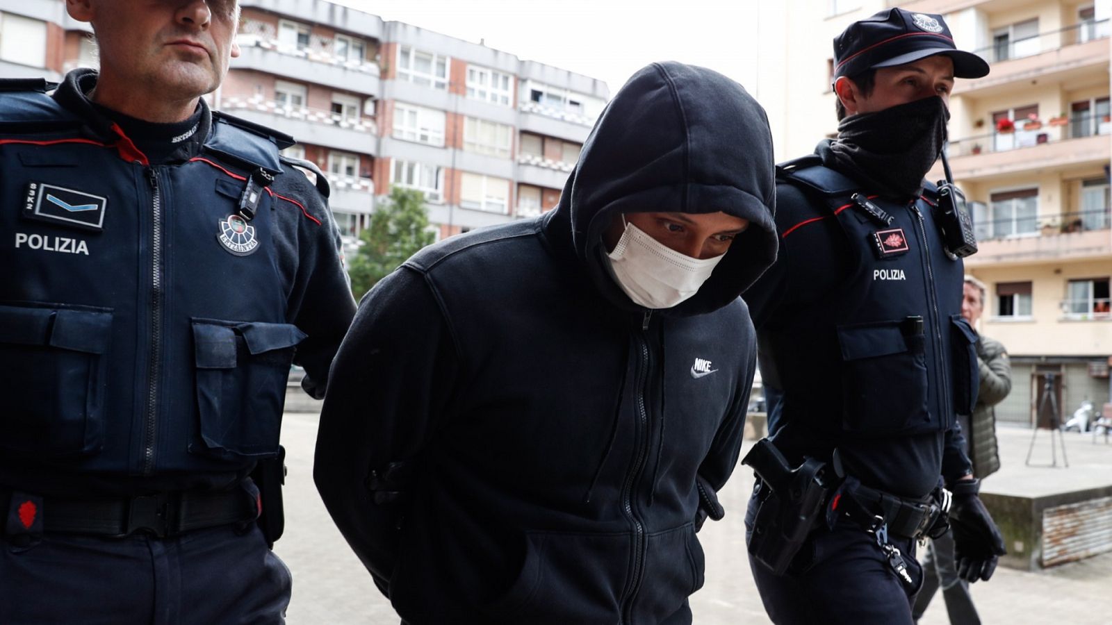 Agentes de la Ertzaintza trasladan al detenido por su presunta vinculación con los asesinatos de hombres en Bilbao tras registrar un piso en la localidad guipuzcoana de Irun (Gipuzkoa).