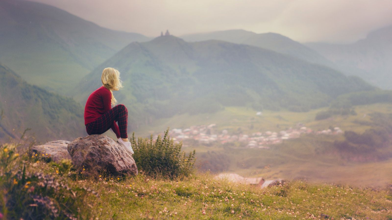 Una mujer contempla el paisaje sentada en una roca