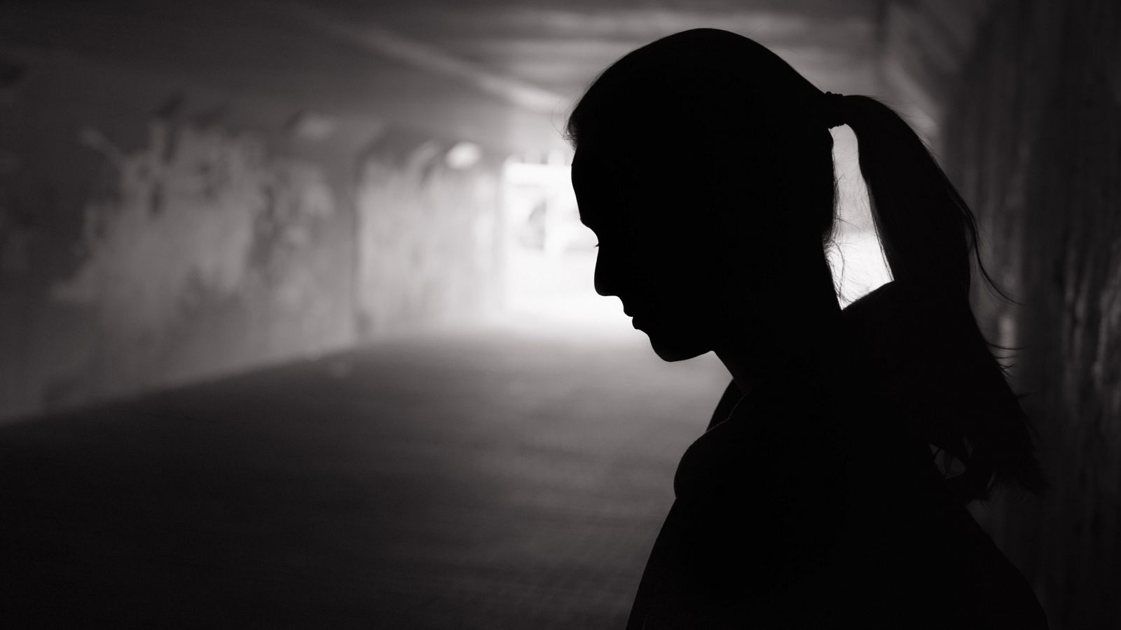 Foto en blanco y negro de la silueta de una mujer en un túnel oscuro