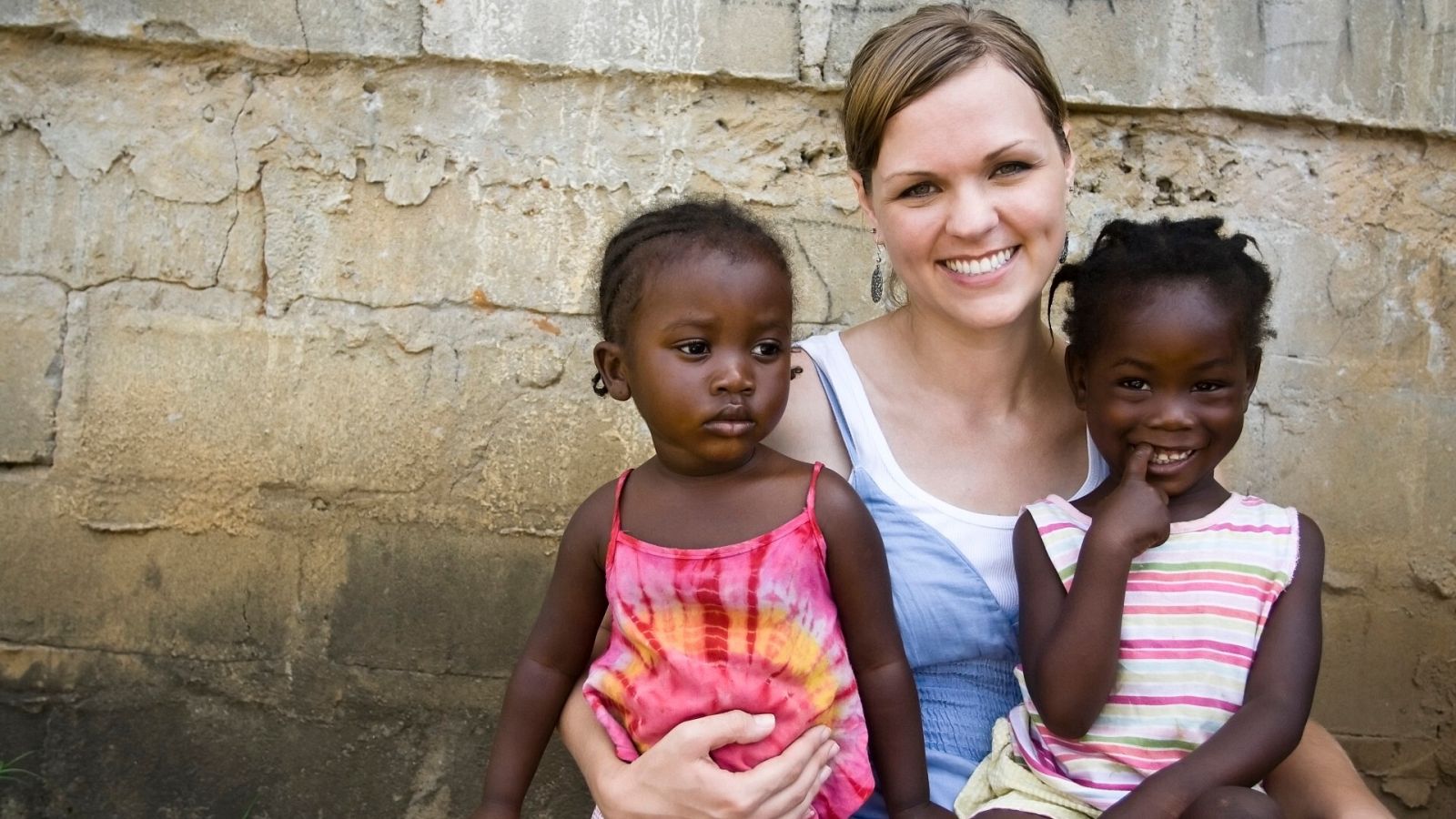 Una mujer occidental abraza a dos menores africanas