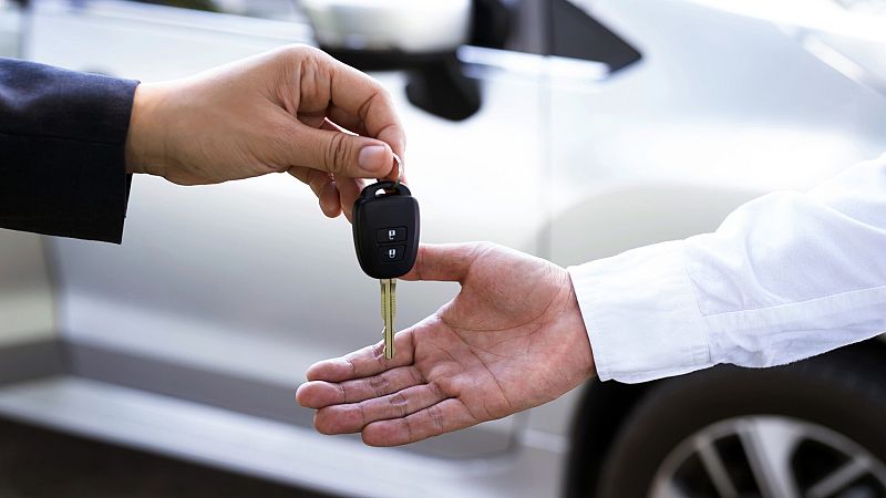 Una persona entrega a otra las llaves de un coche