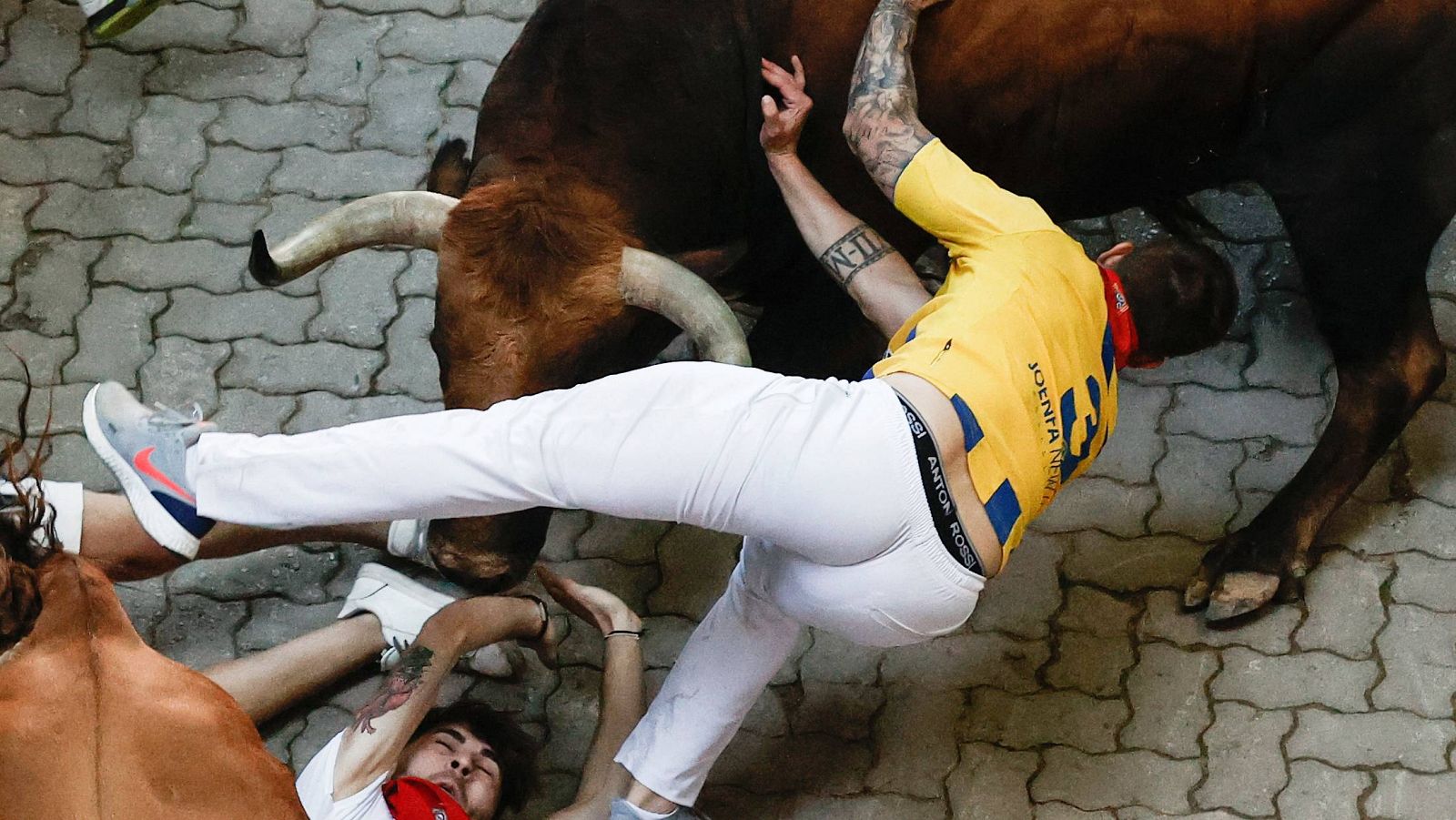 Un mozo choca contra uno de los toros volteados en el quinto encierro de los Sanfermines.