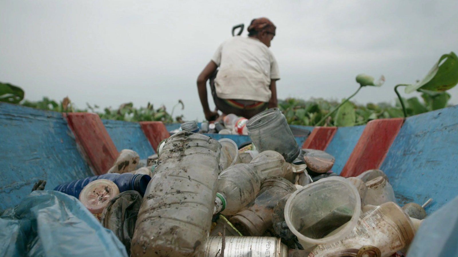 Un pescador recolectando botellas de plástico en el río Citarum