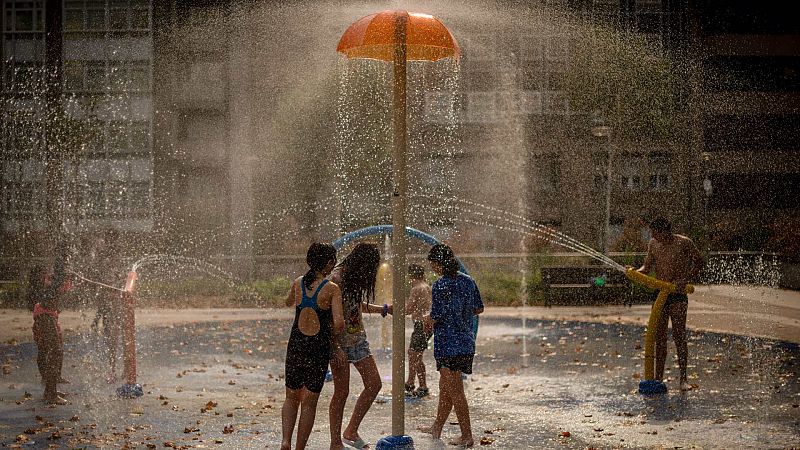 Varios niños se refrescan con una fuente de un parque público