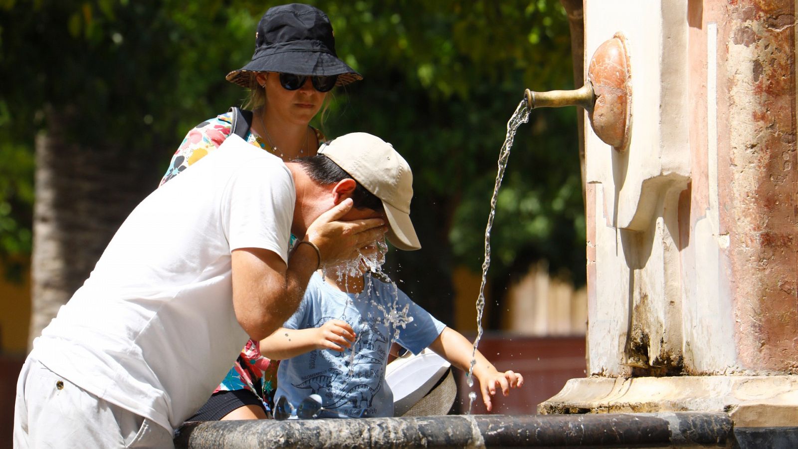 Unos turistas se refrescan en una de las fuentes del patio de los naranjos de la Mezquita-Catedral de Córdoba.