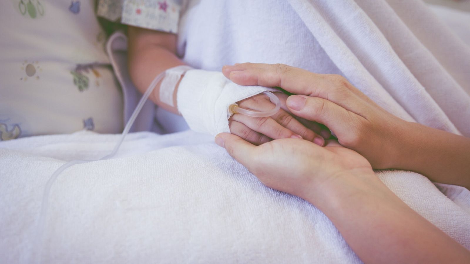 Un adulto toma las manos de un niño ingresado en el hospital, en una imagen de archivo.