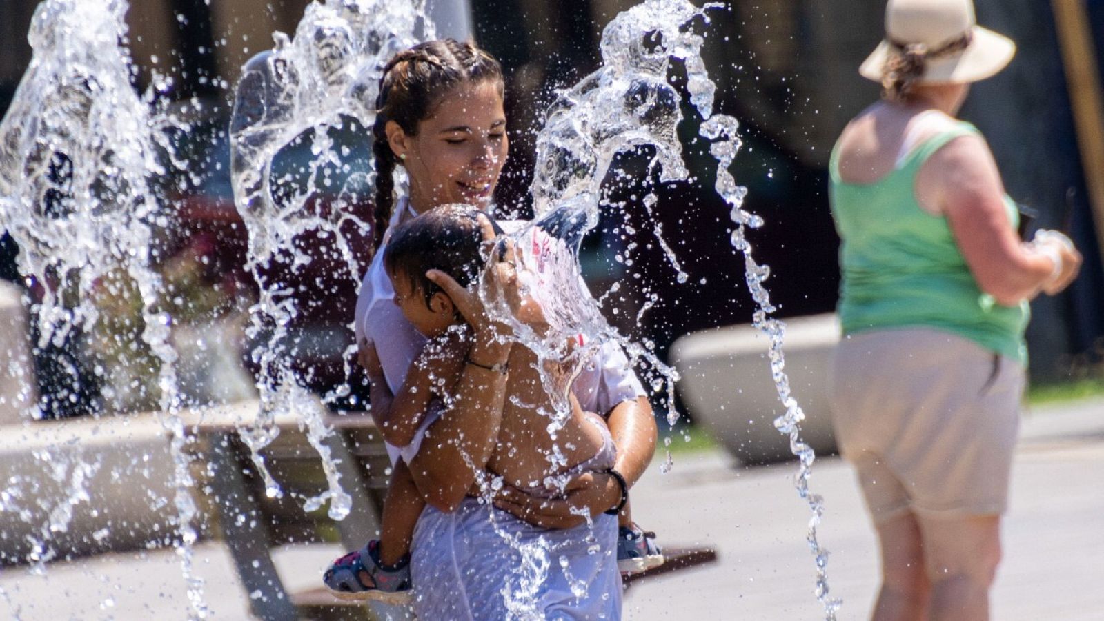 Unos niños se refrescan con los chorros de una escultura acuática en Palma de Mallorca