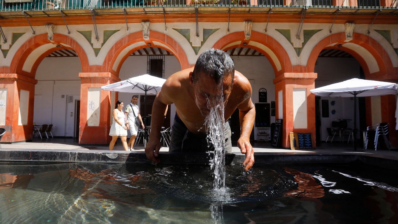 Un hombre se refresca en la fuente de la plaza de la Corredera de Córdoba