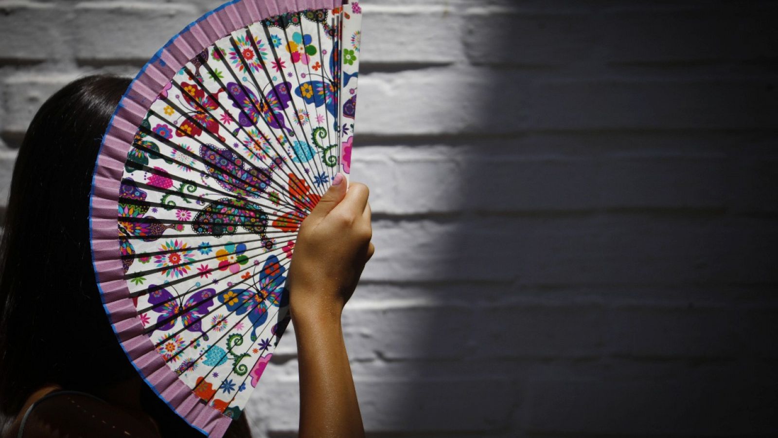 Una mujer se protege del sol con un abanico de las altas temperaturas en Córdoba