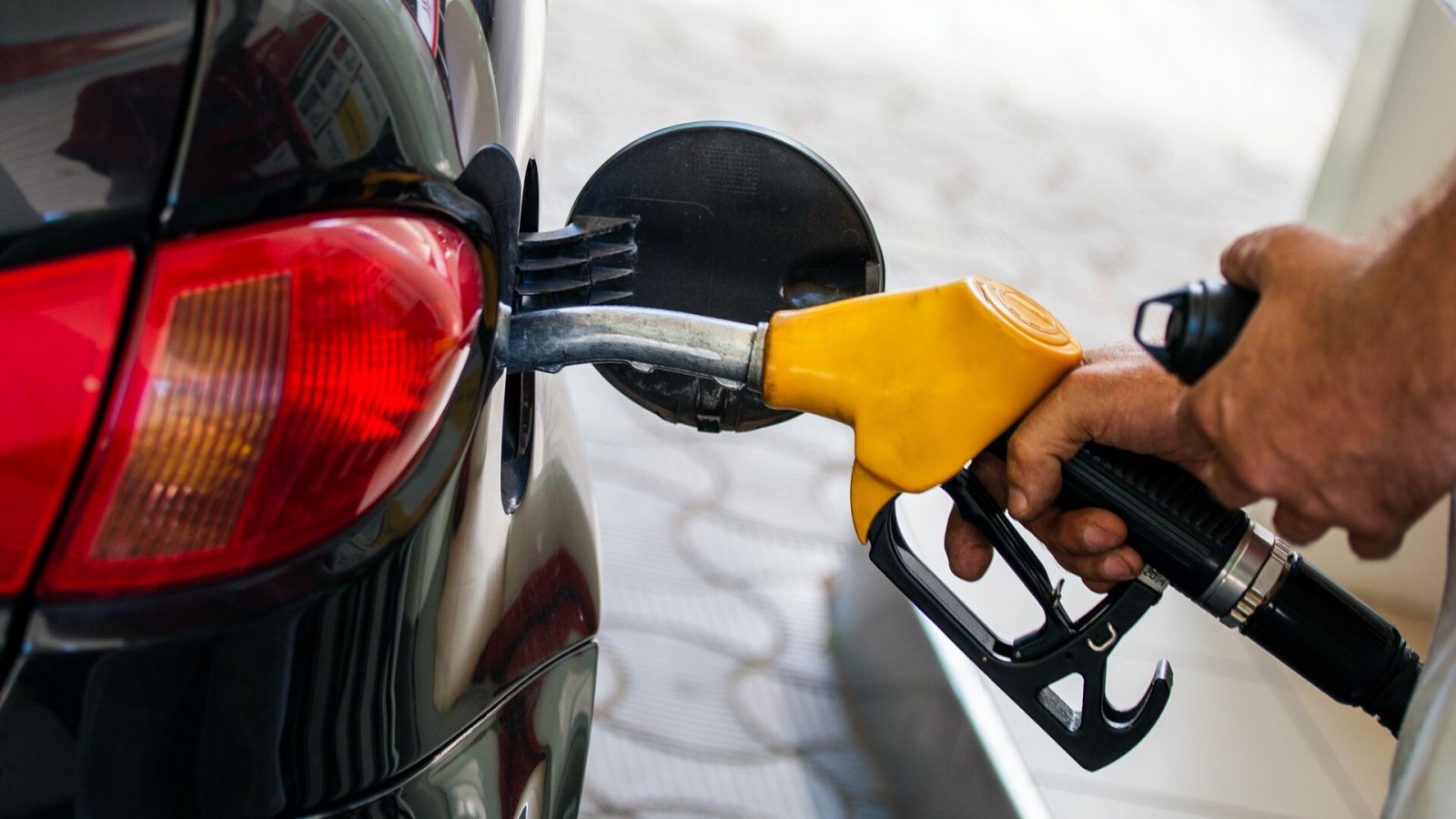 Una mano reposta combustible en un coche.