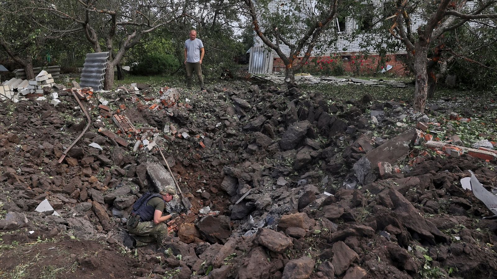 Un policía inspecciona el cráter dejado por el impacto de un misil cerca de una vivienda en Járkov