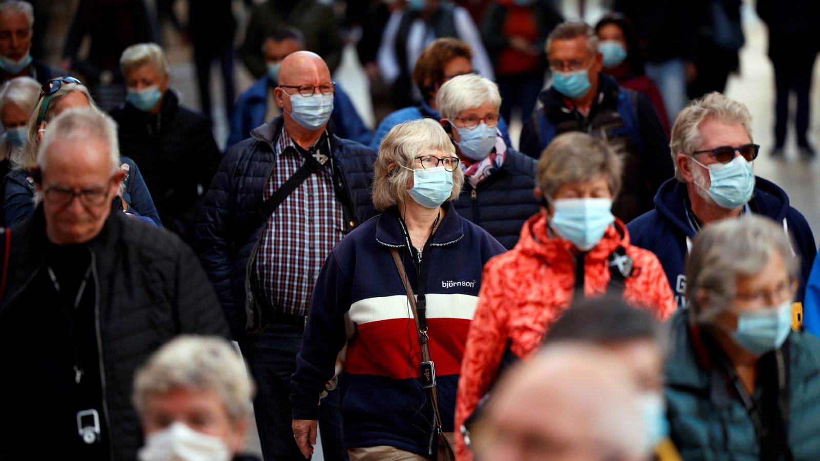 Viandantes caminan con mascarilla en una calle repleta del centro de Valencia durante la pandemia de coronavirus
