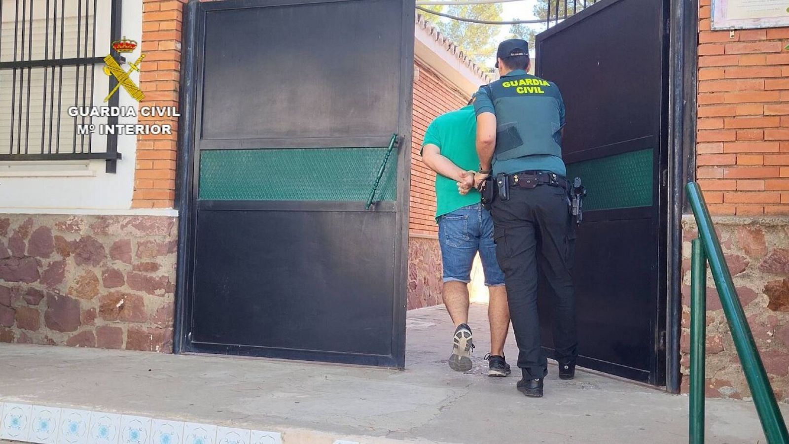 Un guardia lleva esposado a un detenido.