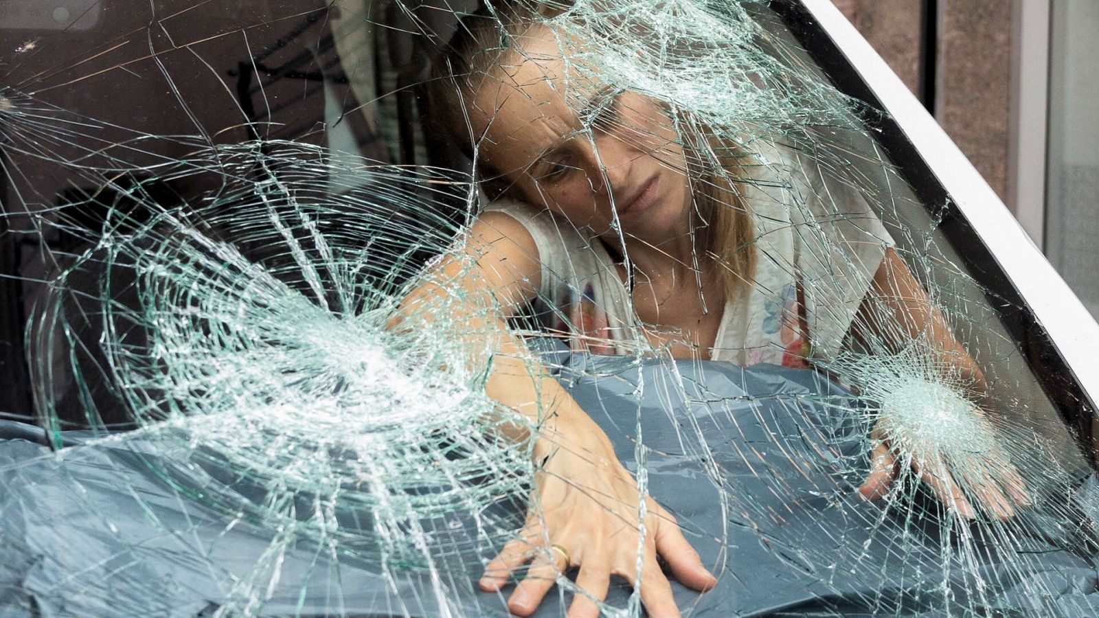 Una vecina de La Bisbal de L'Empordà, en Girona, observa la luna de su coche dañada por el granizo